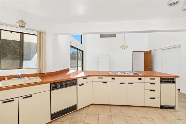 kitchen with light tile patterned floors, white appliances, a sink, and pendant lighting