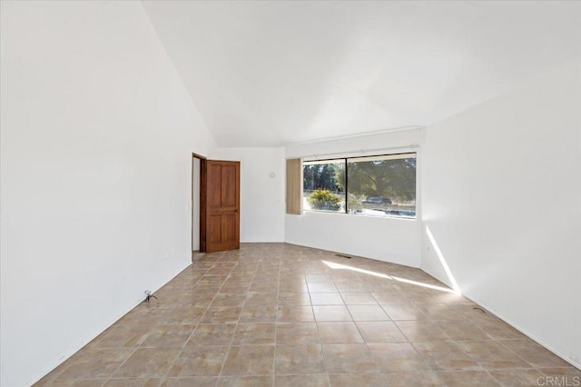 spare room featuring light tile patterned floors and lofted ceiling