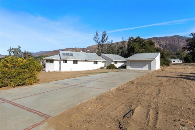 ranch-style home featuring a mountain view, a detached garage, and an outdoor structure