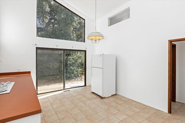 unfurnished dining area with light tile patterned flooring and a high ceiling