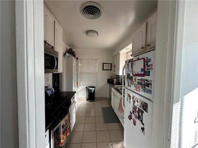 kitchen featuring light tile patterned floors, white fridge, and white cabinetry