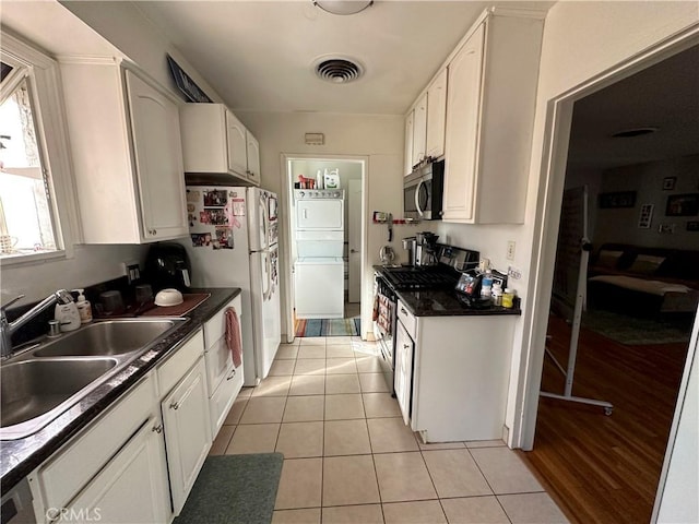 kitchen with white fridge, sink, white cabinetry, light tile patterned floors, and range