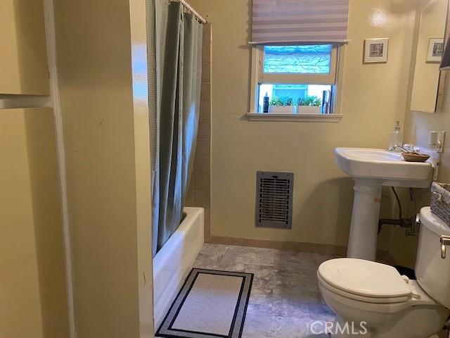 bathroom with toilet and shower / tub combo with curtain