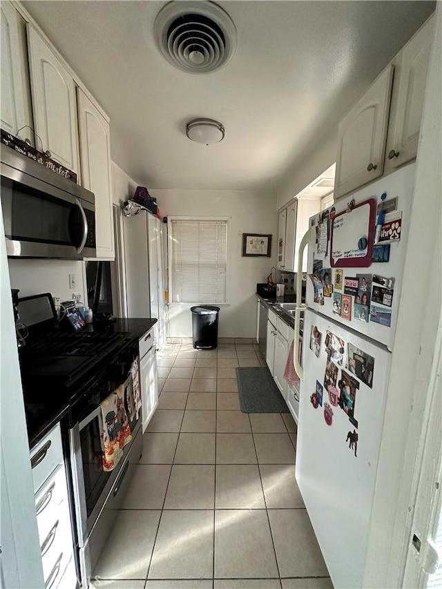 kitchen featuring tile patterned flooring, appliances with stainless steel finishes, and white cabinetry