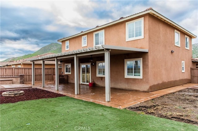 back of house featuring a yard, a patio area, a mountain view, and a fire pit