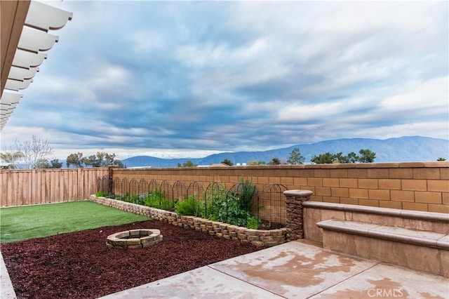 view of yard with a mountain view, a patio area, and an outdoor fire pit