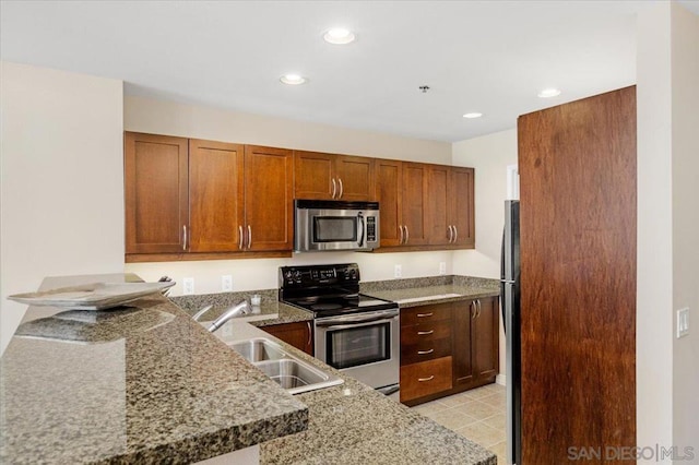 kitchen featuring light tile patterned floors, kitchen peninsula, stainless steel appliances, light stone countertops, and sink