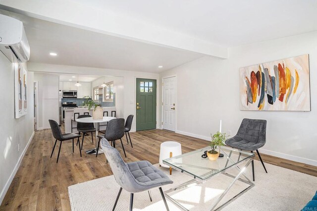 living room featuring a wall unit AC, beam ceiling, and hardwood / wood-style flooring