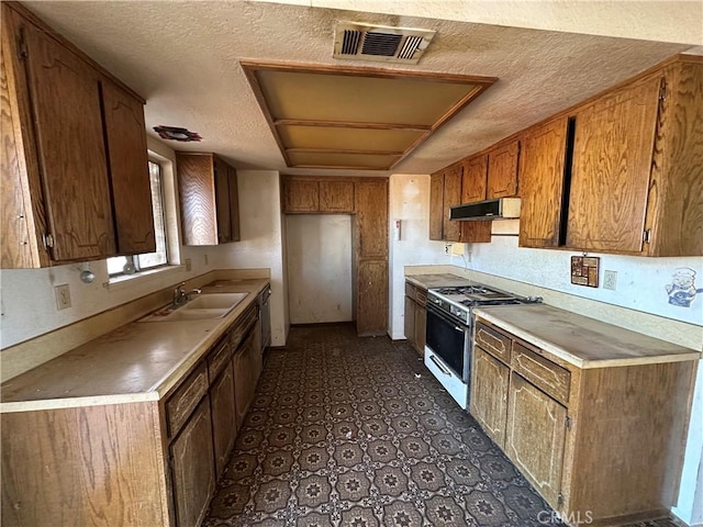 kitchen featuring dishwasher, white range with gas stovetop, sink, and a textured ceiling