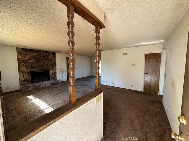 unfurnished living room featuring a fireplace, dark carpet, and a textured ceiling