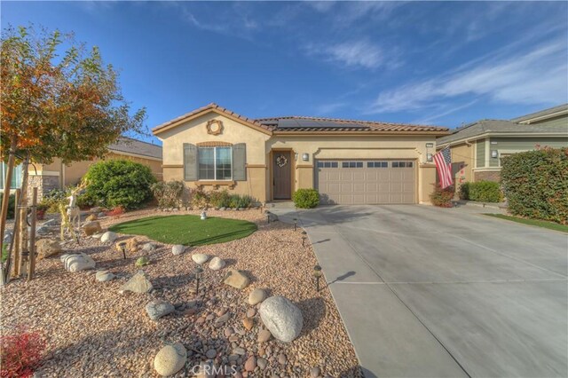 mediterranean / spanish-style home featuring a front lawn, a garage, and solar panels