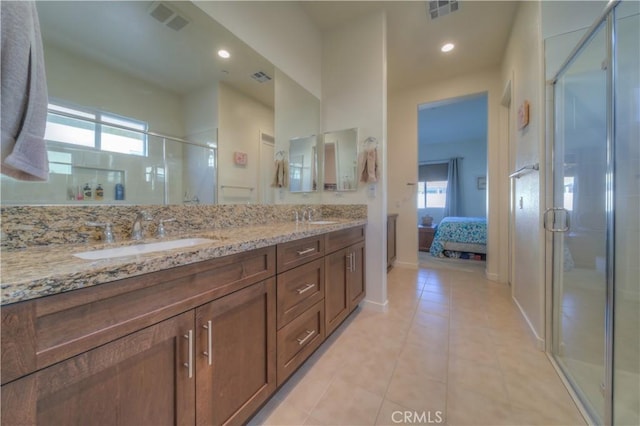 bathroom with a shower with shower door, vanity, and tile patterned flooring