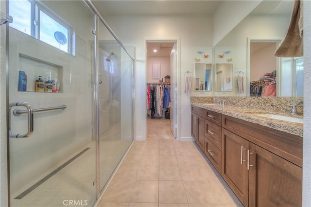 bathroom with tile patterned floors, a shower with door, and vanity