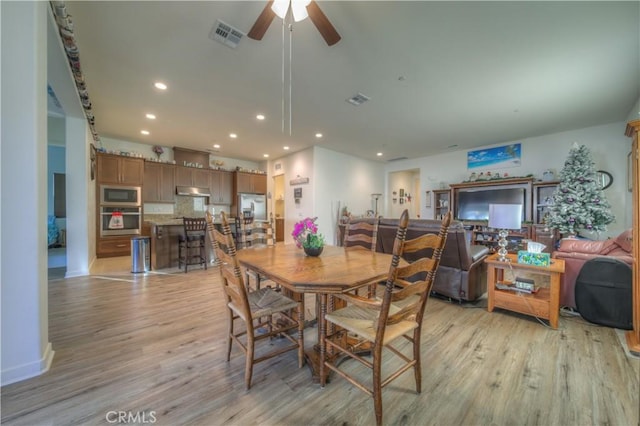 dining area with light wood-type flooring and ceiling fan