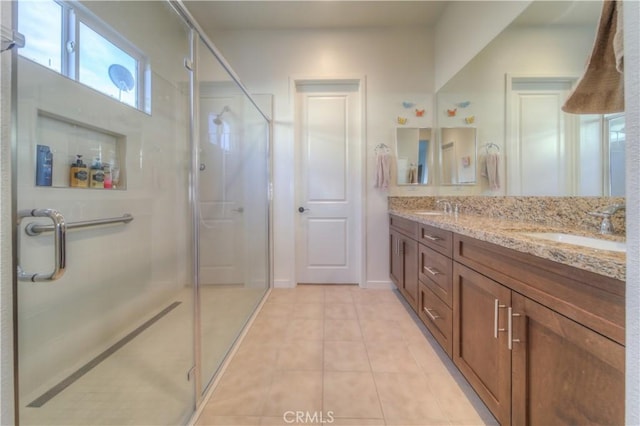 bathroom with a shower with door, tile patterned flooring, and vanity