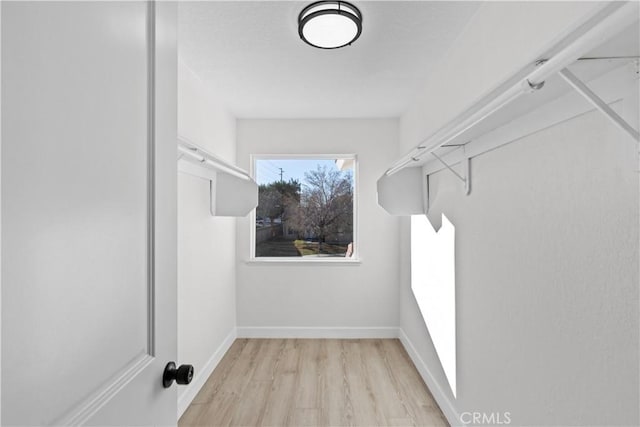 walk in closet with light hardwood / wood-style flooring