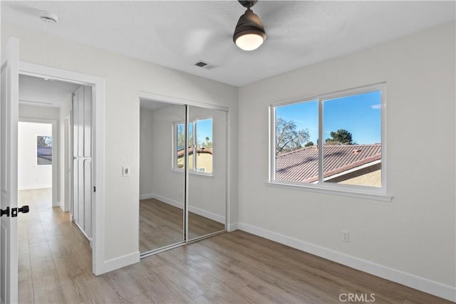 unfurnished bedroom featuring ceiling fan, a closet, and light wood-type flooring