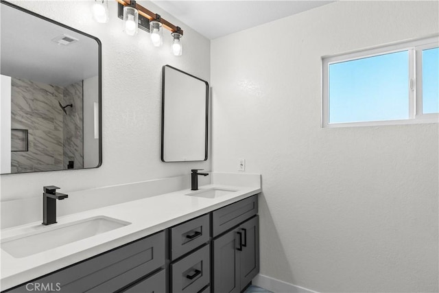 bathroom featuring tiled shower and vanity