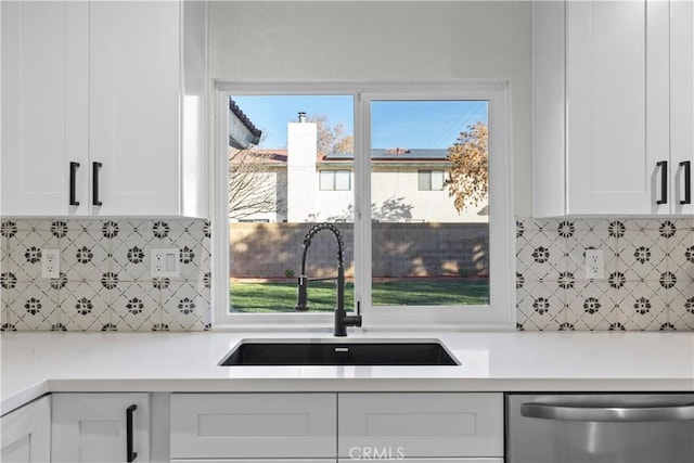 kitchen with dishwasher, white cabinets, backsplash, and sink