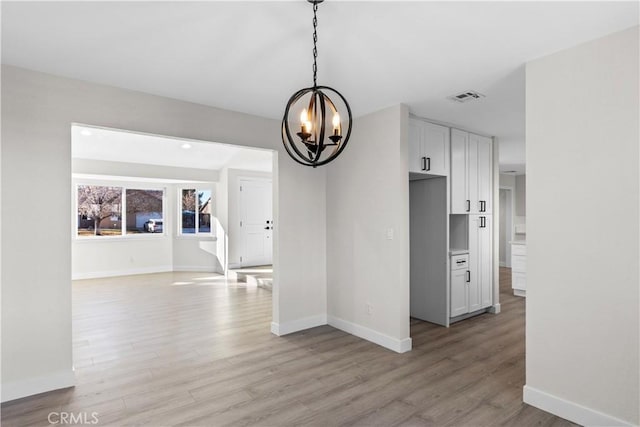 unfurnished dining area with light wood-type flooring and a notable chandelier