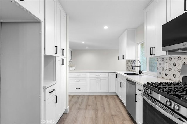 kitchen featuring light hardwood / wood-style floors, decorative backsplash, sink, appliances with stainless steel finishes, and white cabinets