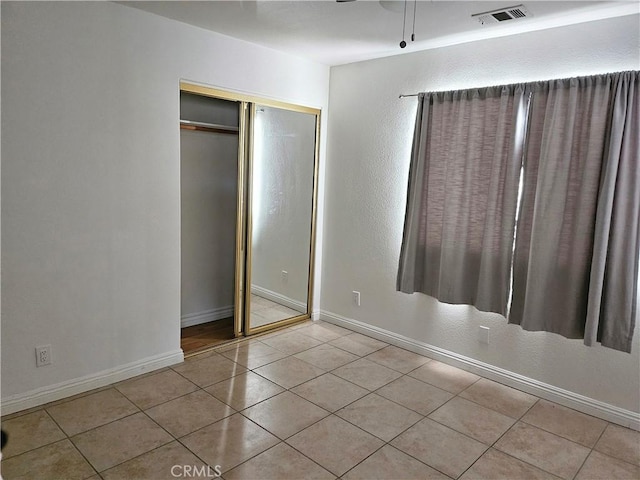 unfurnished bedroom with a closet, light tile patterned floors, and ceiling fan