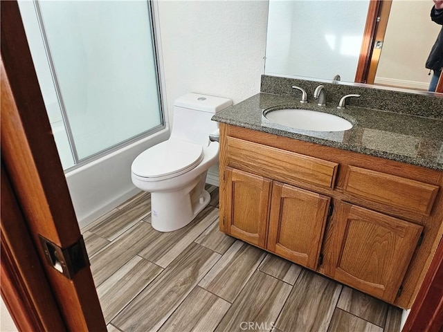 full bathroom featuring combined bath / shower with glass door, vanity, and toilet