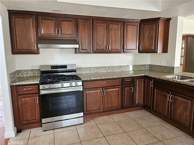 kitchen featuring light tile patterned floors, gas stove, light stone counters, and extractor fan