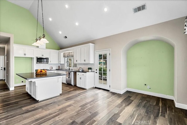 kitchen with dark wood-type flooring, white cabinetry, decorative backsplash, and a kitchen island