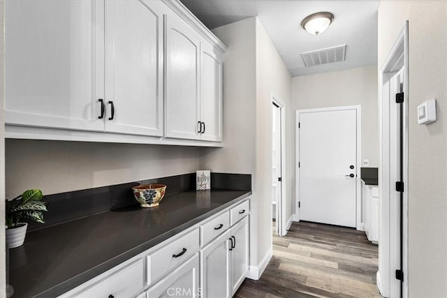 bar featuring dark hardwood / wood-style floors and white cabinetry