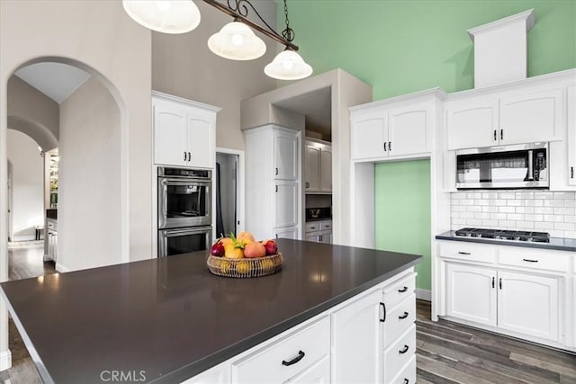 kitchen featuring pendant lighting, appliances with stainless steel finishes, white cabinetry, dark hardwood / wood-style flooring, and tasteful backsplash