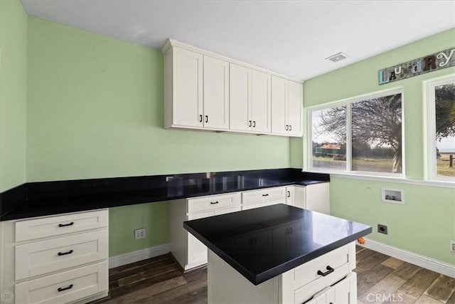 kitchen featuring dark hardwood / wood-style flooring, built in desk, white cabinets, and a center island