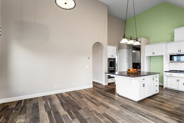 kitchen featuring high vaulted ceiling, backsplash, white cabinetry, and stainless steel appliances