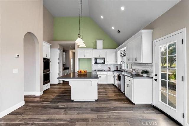 kitchen with tasteful backsplash, white cabinets, appliances with stainless steel finishes, and a kitchen island