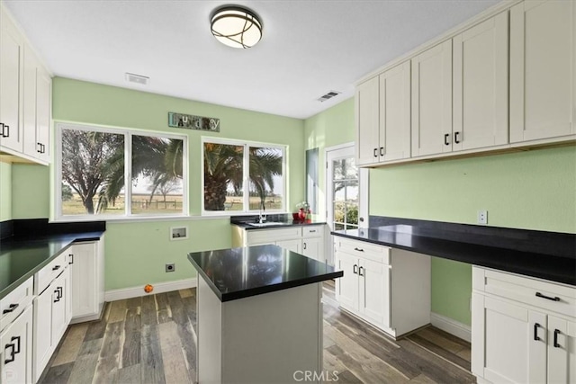 kitchen with white cabinets, dark hardwood / wood-style floors, sink, and a kitchen island