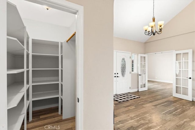 interior space featuring an inviting chandelier, hardwood / wood-style floors, lofted ceiling, and french doors