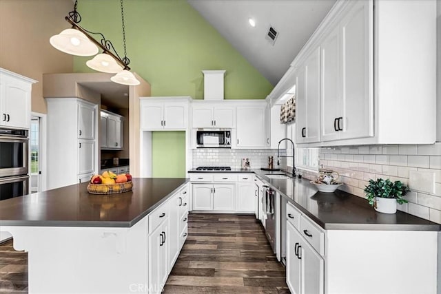 kitchen with high vaulted ceiling, white cabinets, sink, and stainless steel appliances