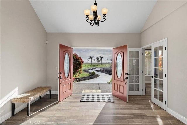 foyer entrance with lofted ceiling, french doors, a chandelier, and wood-type flooring