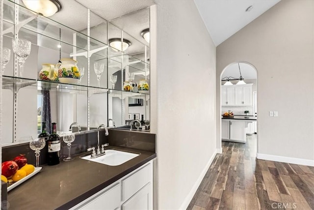 bar with lofted ceiling, white cabinetry, dark hardwood / wood-style flooring, decorative backsplash, and sink