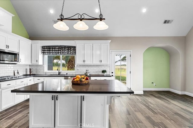 kitchen featuring white cabinetry, a kitchen island, stainless steel appliances, and pendant lighting