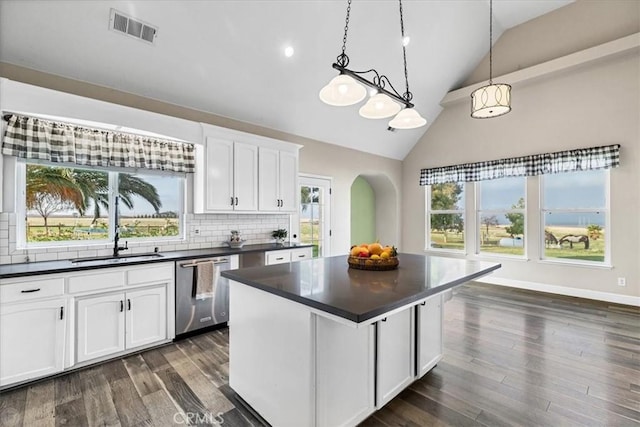 kitchen featuring backsplash, dark hardwood / wood-style floors, pendant lighting, stainless steel dishwasher, and white cabinets