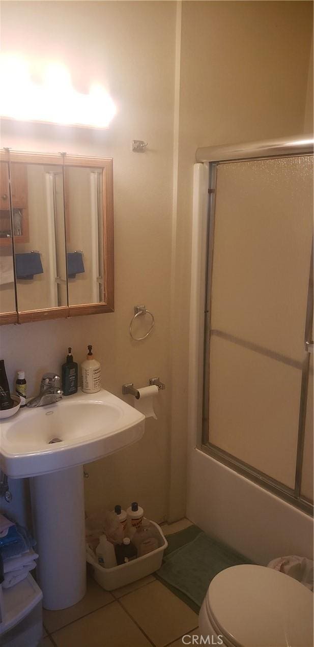 full bathroom featuring sink, enclosed tub / shower combo, toilet, and tile patterned flooring