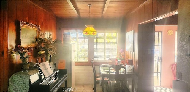 dining area with wooden ceiling, wood walls, and beamed ceiling