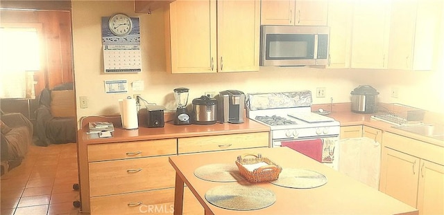 kitchen with tile patterned flooring, sink, and white range with gas cooktop