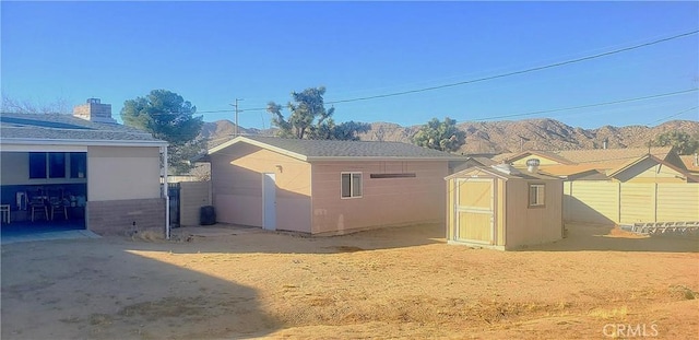 rear view of property with a storage shed and a mountain view