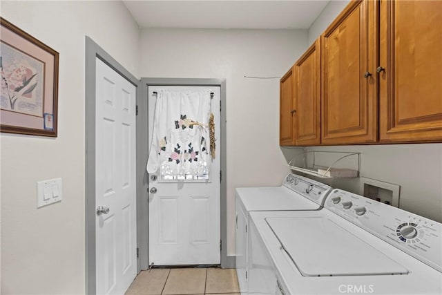 clothes washing area with cabinets, washing machine and dryer, and light tile patterned floors