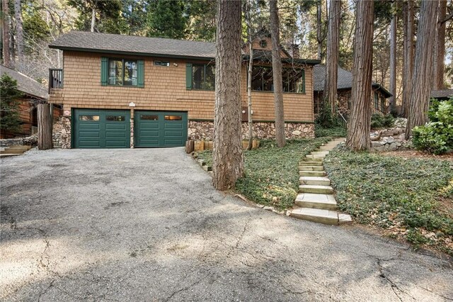 801 Kuffel Canyon Rd, Lake Arrowhead, CA 92385 - chalet / cabin with driveway, a garage, roof with shingles, and stone siding