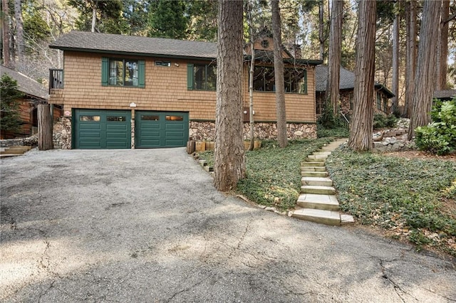 801 Kuffel Canyon Rd, Lake Arrowhead, CA 92385 - rustic home with driveway, an attached garage, a shingled roof, and stone siding