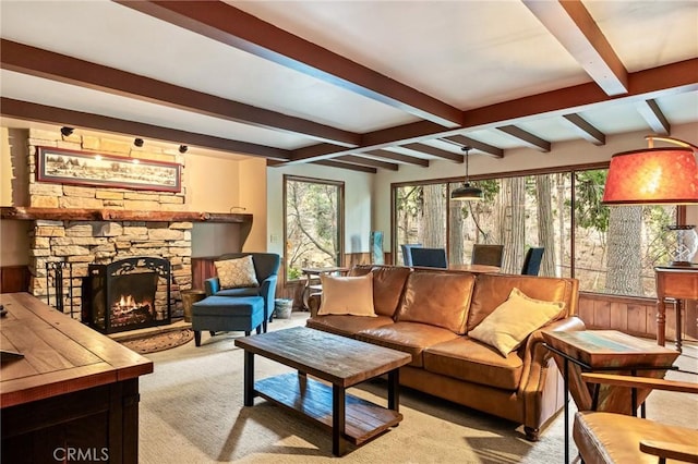 carpeted living room featuring beam ceiling and a stone fireplace