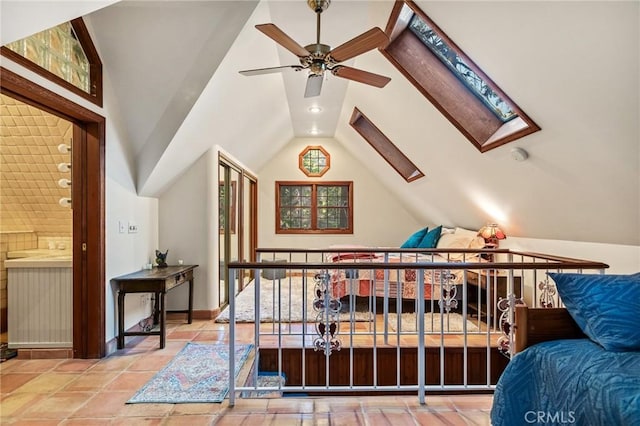 tiled bedroom with ceiling fan, connected bathroom, and lofted ceiling with skylight